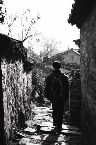 背着背包的人行走在古老小巷中
