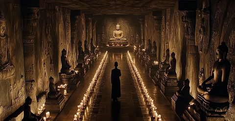 佛窟内一人独行烛光映照佛像肃穆神秘