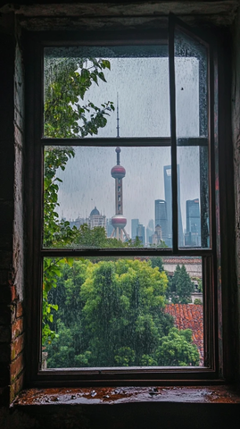 透过老旧窗户看雨中东方明珠塔